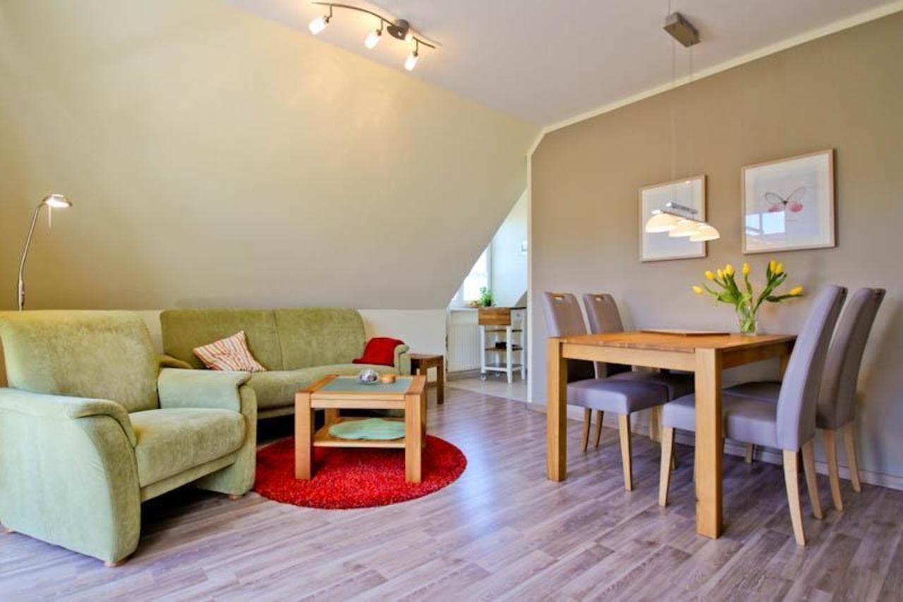 Wohn- und Essbereich mit Sofa, Tisch und Stühlen. Holzboden und roter Teppich.