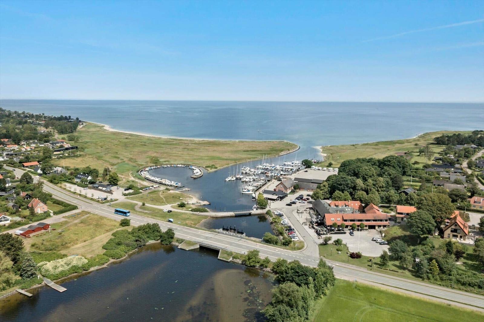 Norsminde Kro mit Terrasse, Sitzgelegenheiten und Steinbecken im Vordergrund.