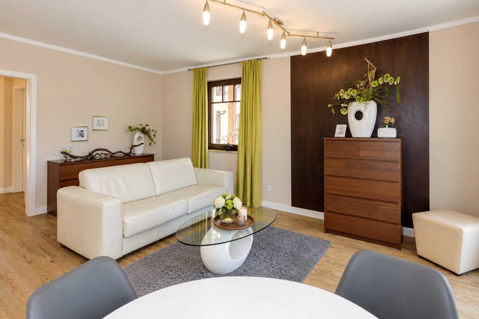Wohnzimmer mit weißem Sofa, Glas-Tisch und Holzmöbeln.