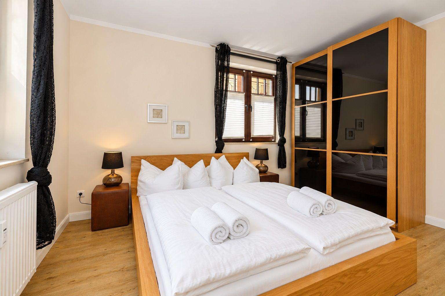 Schlafzimmer mit Doppelbett, Holzmöbeln und Fenster mit Jalousien.