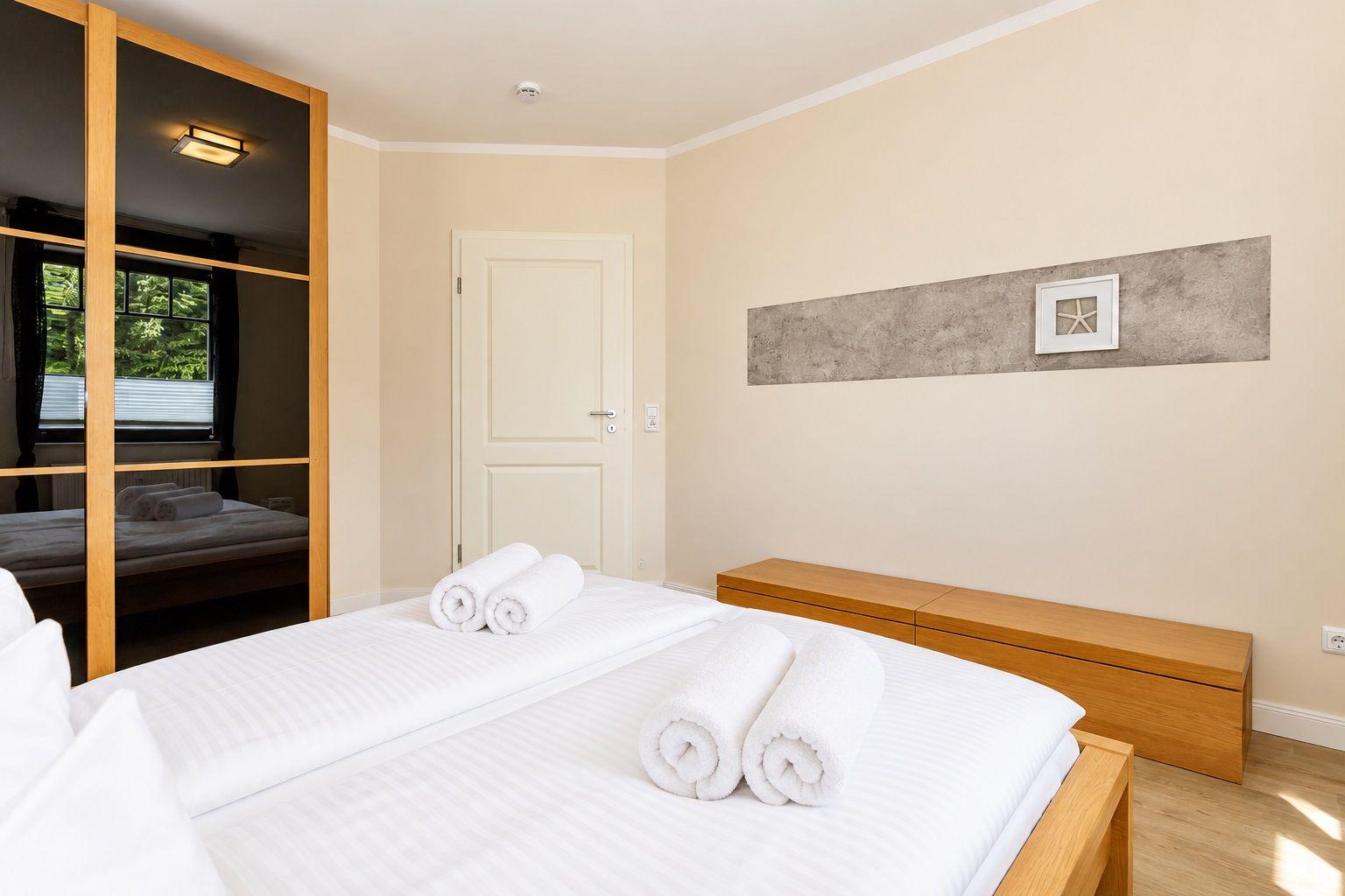 Schlafzimmer mit Bett, Holzschrank und Wanddekoration.