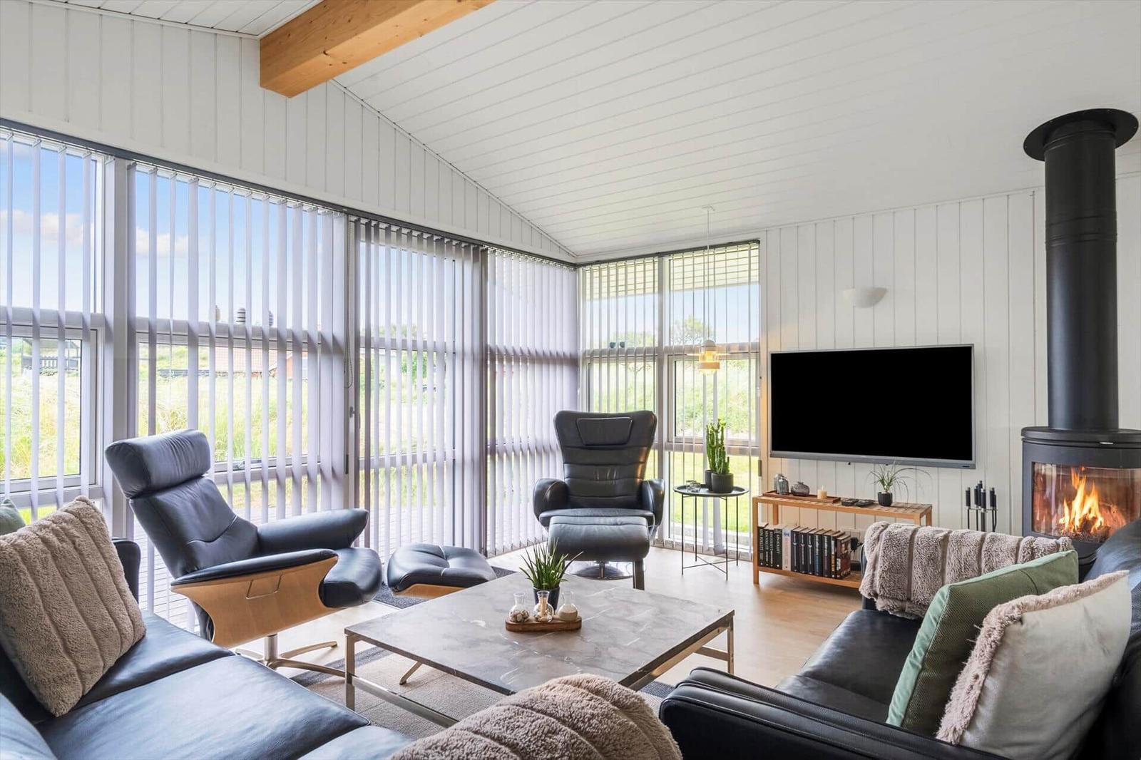 Wohnzimmer mit Sofa, Fernseher und Fenstern zum Blick auf die Umgebung.