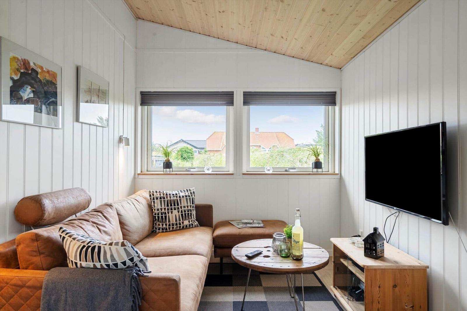 Essbereich mit Holztisch und Stühlen. Küche mit Barhocker. Dachfenster. Wohnbereich mit Sofa.