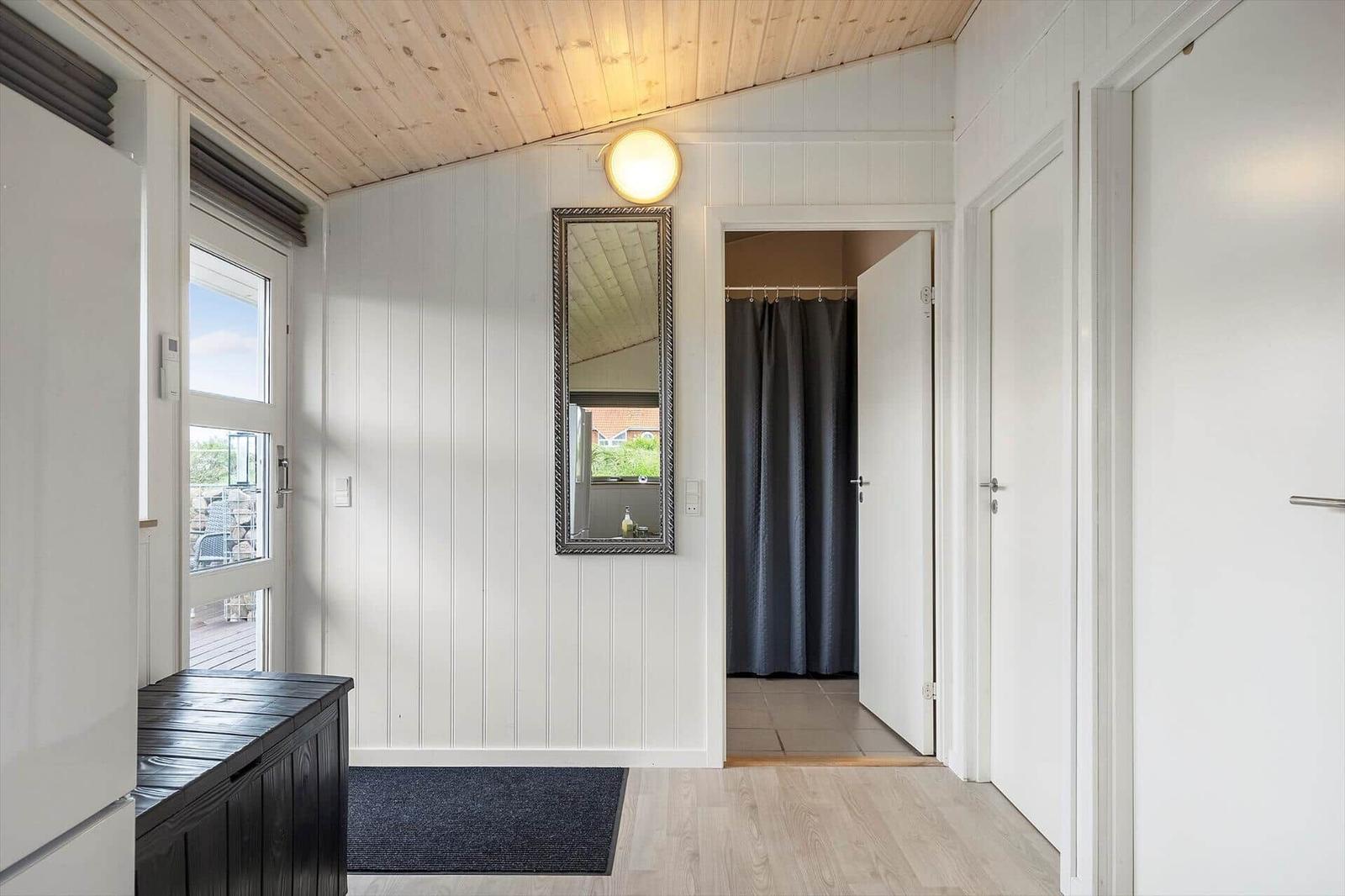 Esszimmer mit Holzstühlen, Tischdecke und Kamin. Fenster bieten Blick auf Grünflächen.