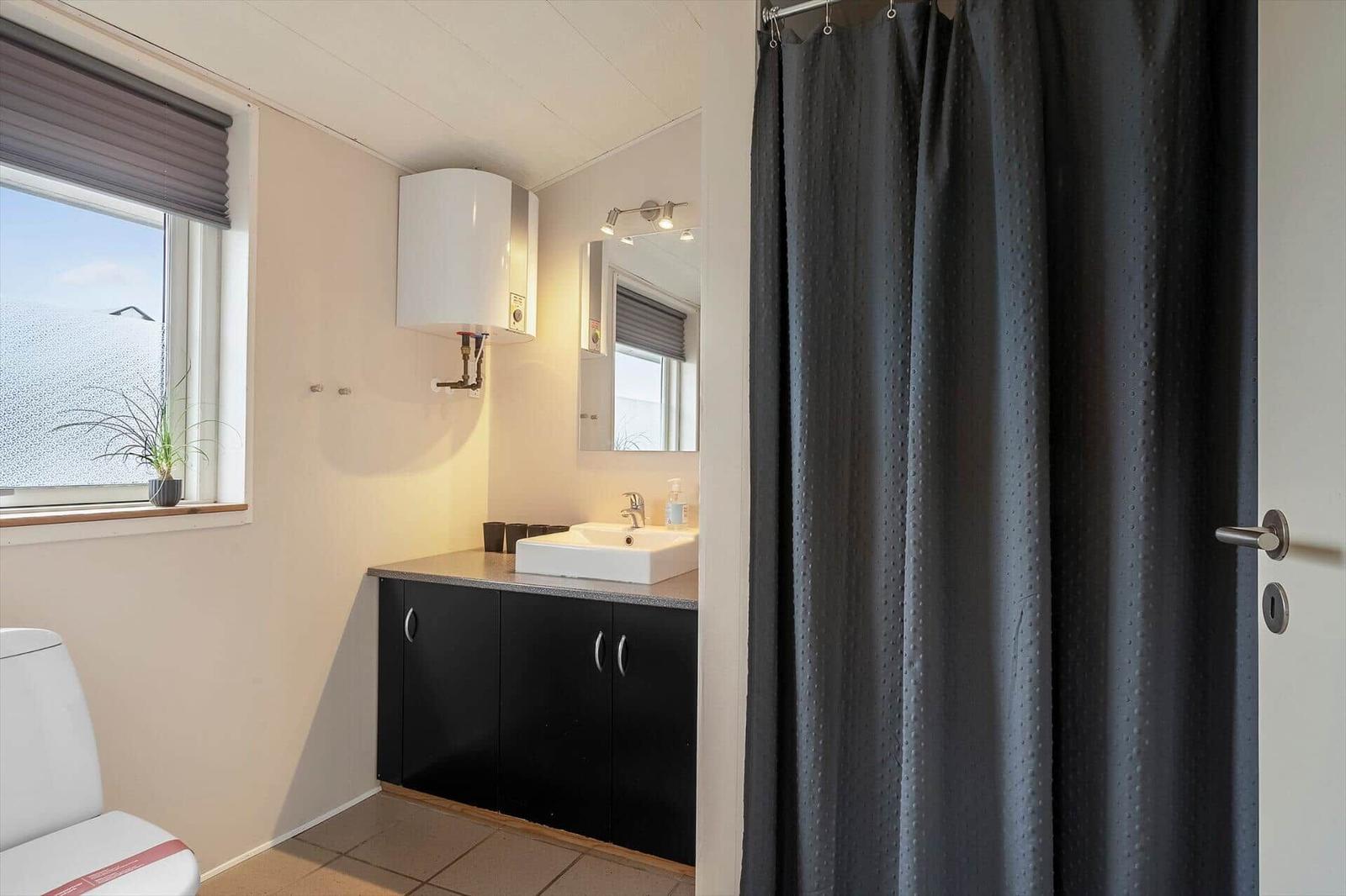 Wohnzimmer mit schwarzer Ledermöbeln, Marmor-Tisch und großen Fenstern.
