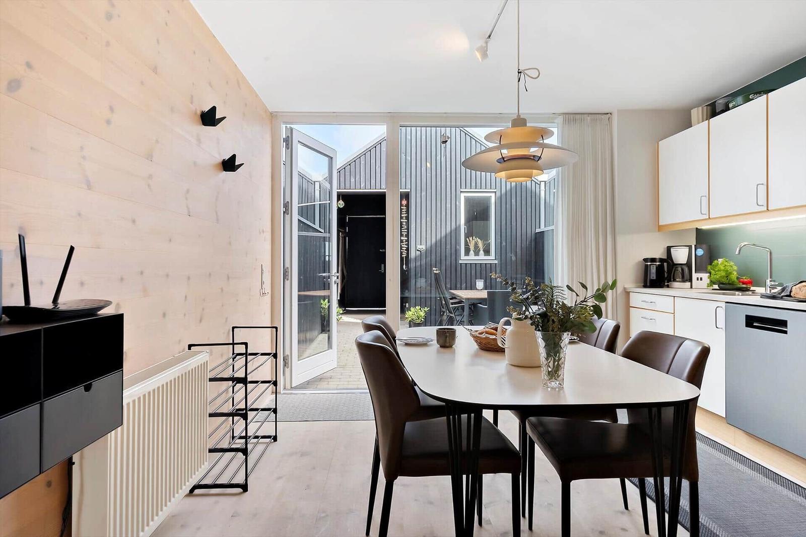 Küche mit Esstisch, Stufen zur oberen Etage und Holzwand.