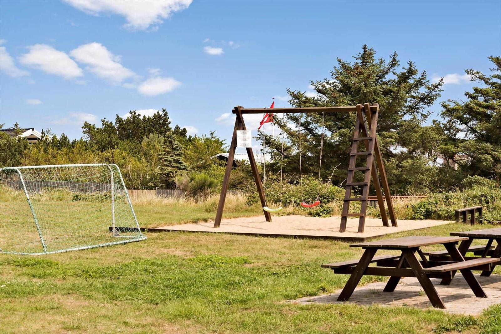 Terrasse mit Lounger, Tisch und Stühlen. Roter Holzausbau im Hintergrund.