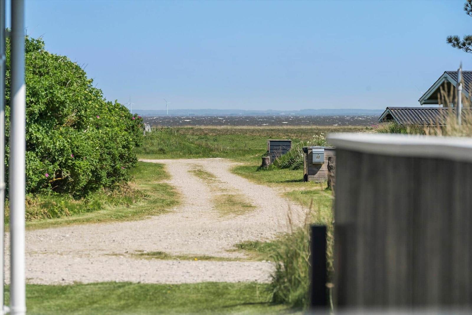 Ausblick auf Strand, Dünen und Leuchtturm an der Küste.