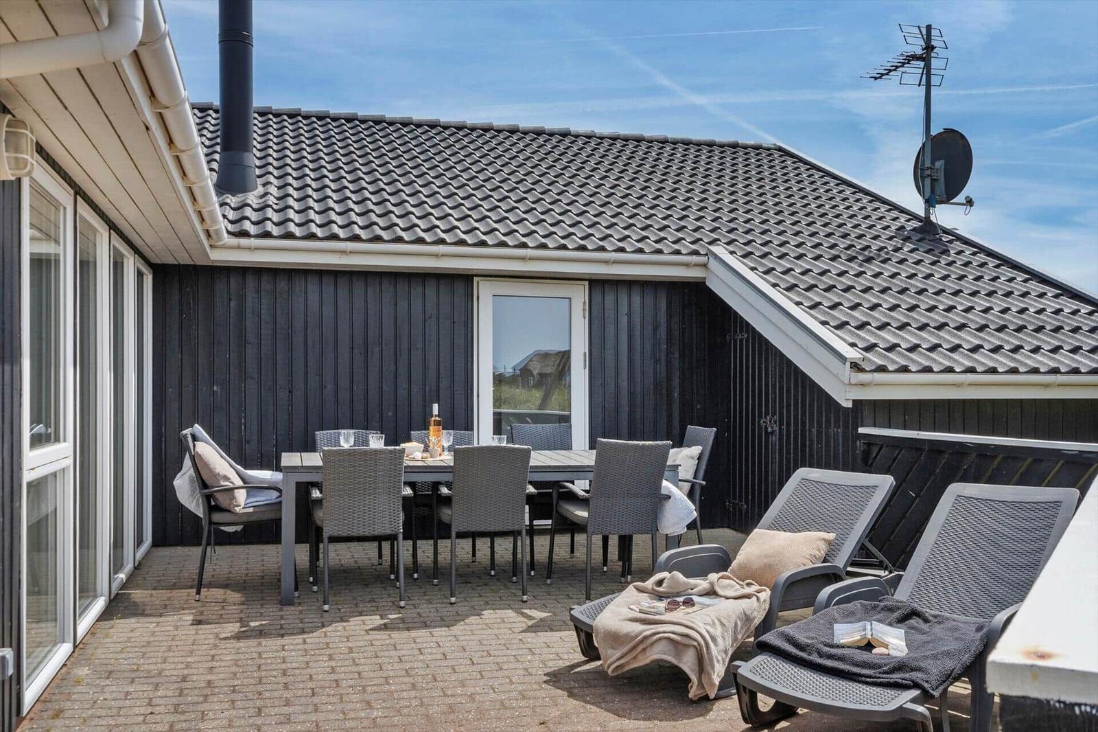 Moderne schwarze Ferienhaus mit Terrasse, Garten und Blick auf den Wald und das Meer.