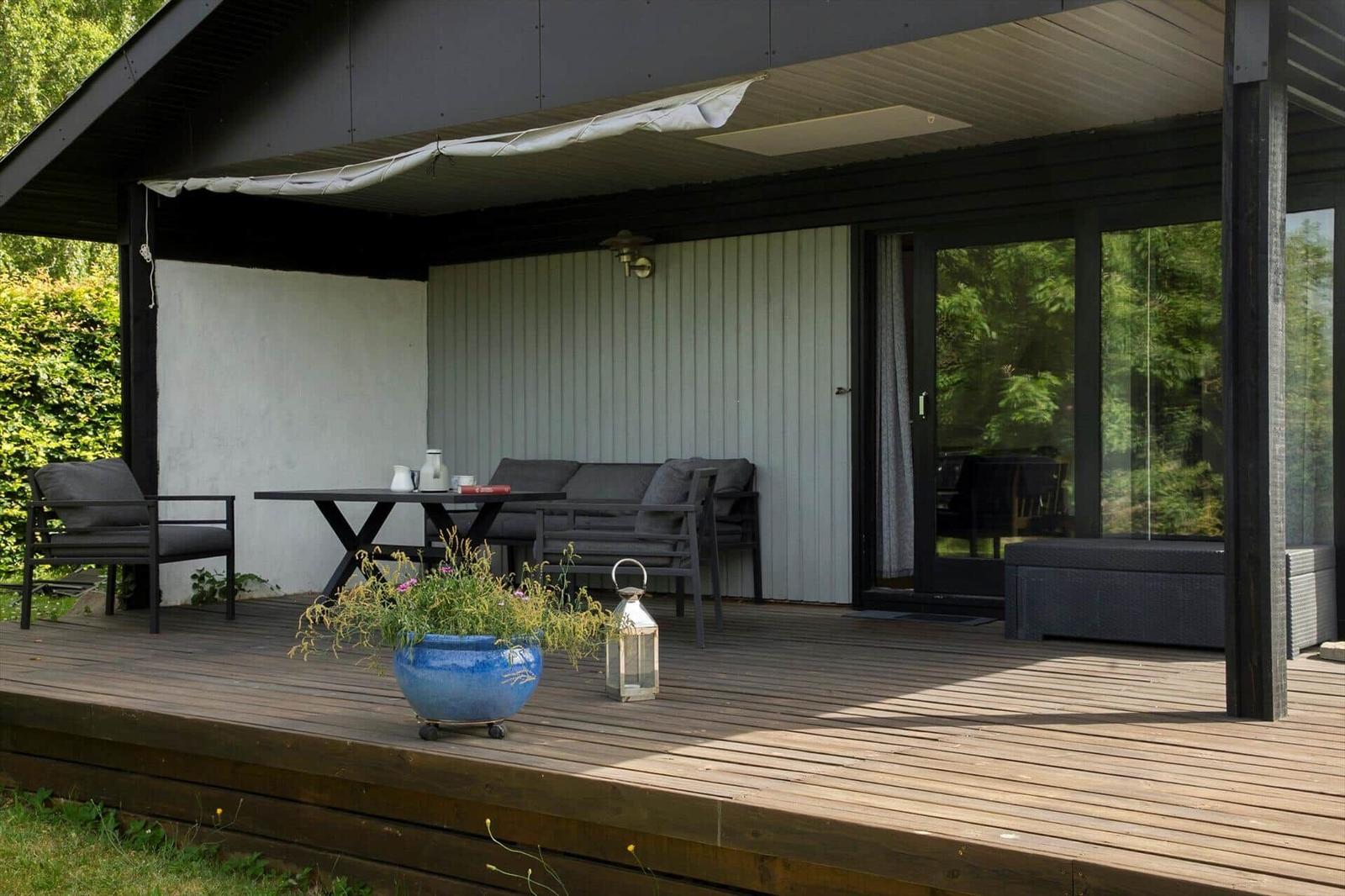 Ein Haus mit Terrasse und Garten. Holzterrasse, Sitzgelegenheiten und Grünflächen.