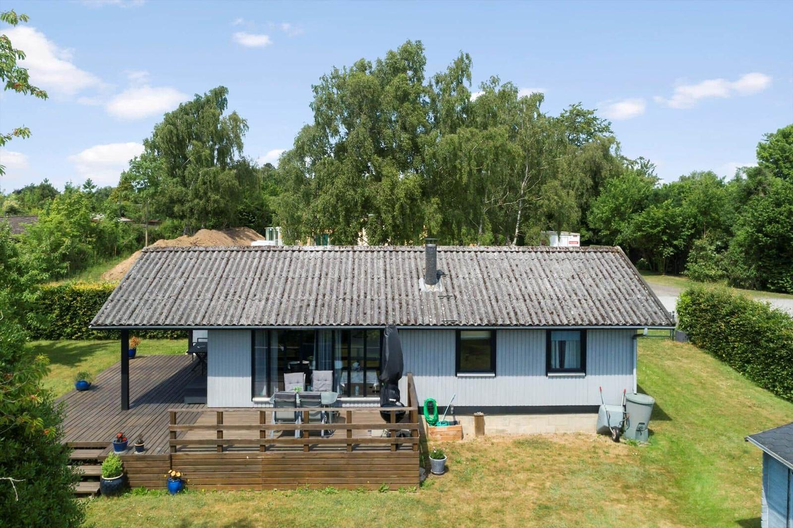 Badezimmer mit blauen Fliesen, Toilette, Dusche und Fenster mit Jalousie.