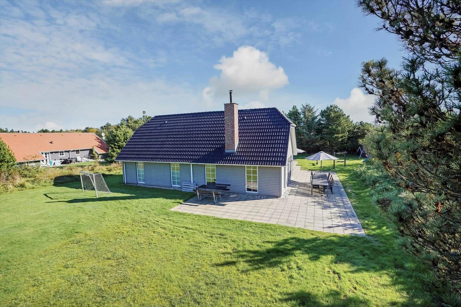 Ein Haus mit blauem Dach und großem Garten. Außenterrasse und Grillmöglichkeit.