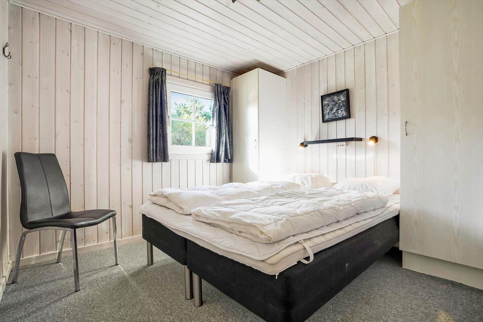 Hallenflur mit Holzboden und weißen Wänden. Tür führt nach draußen.