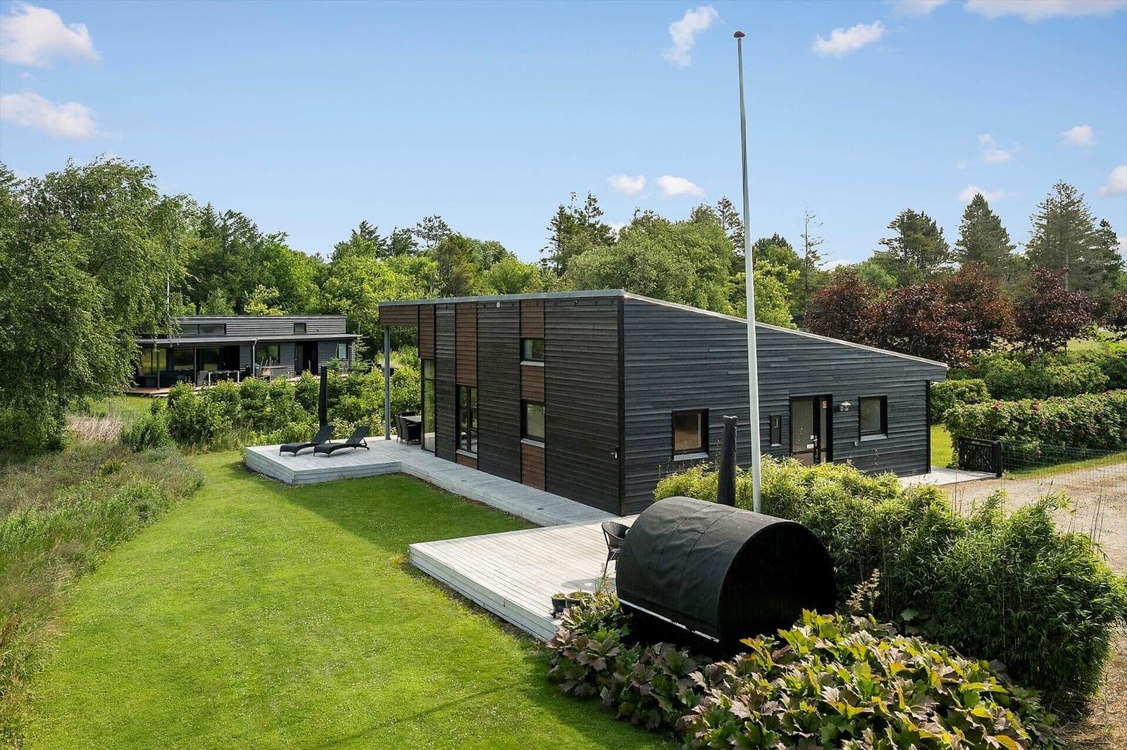 Modern villa with terrace, garden, and view of a lake.