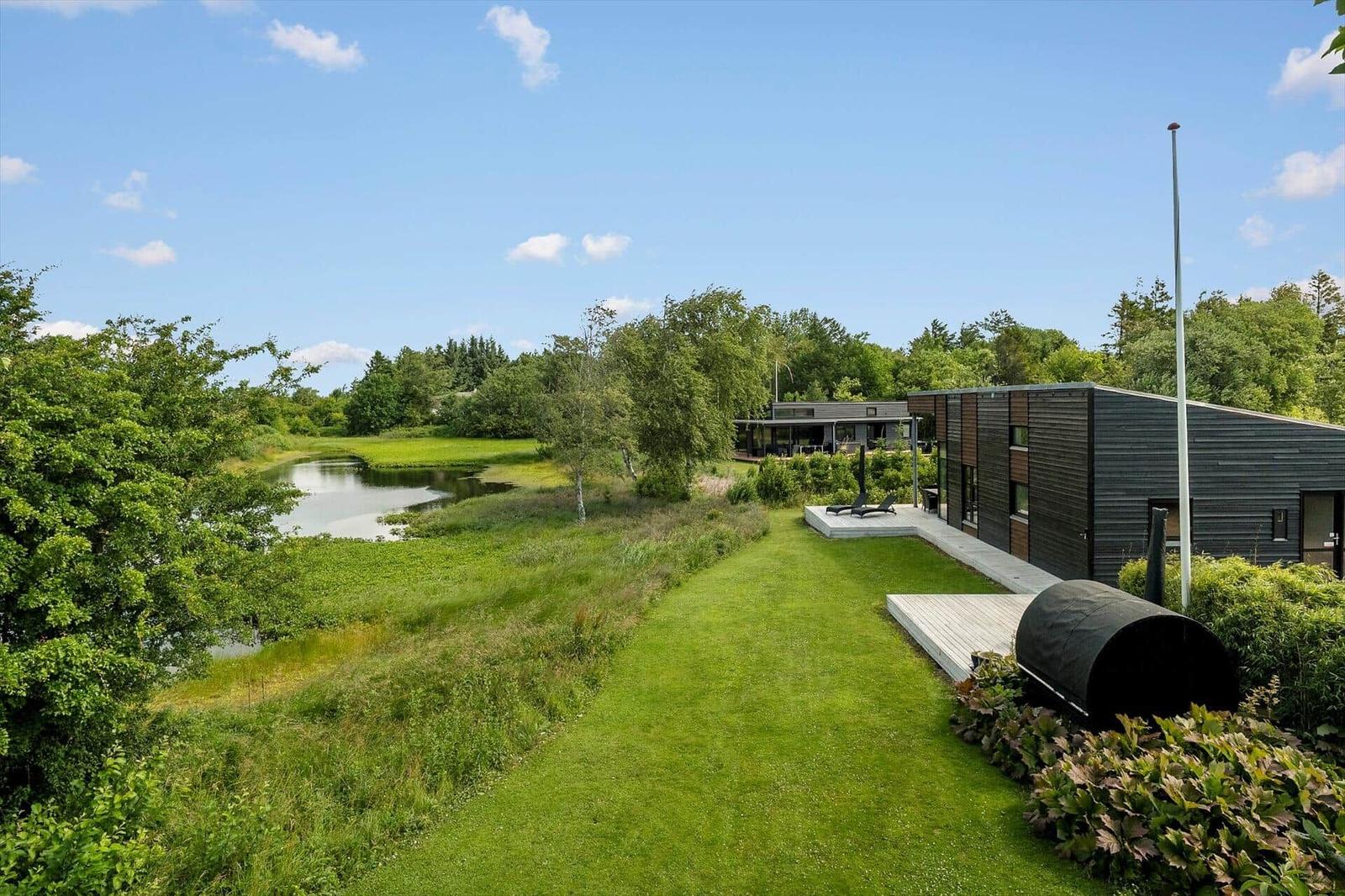 Modern wooden houses with terrace and garden. Black cladding and green surroundings.