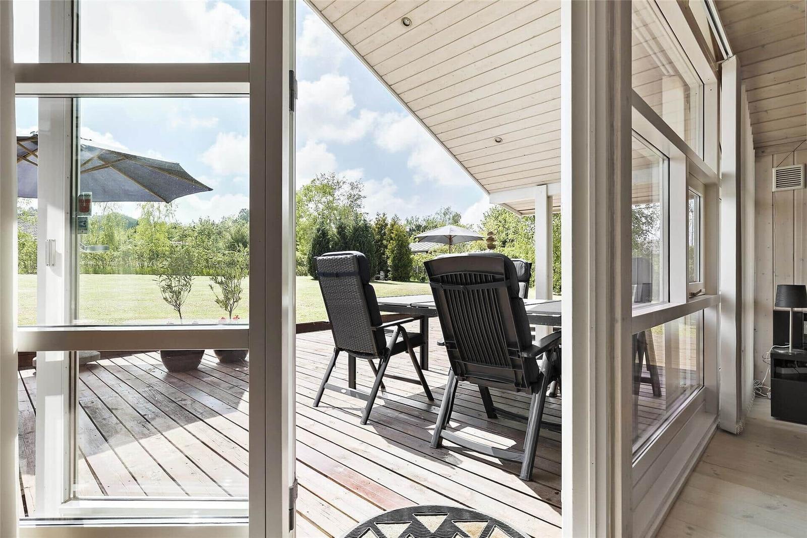 Schlafzimmer mit Holzwand, Bett und Fenster mit Blick auf Garten