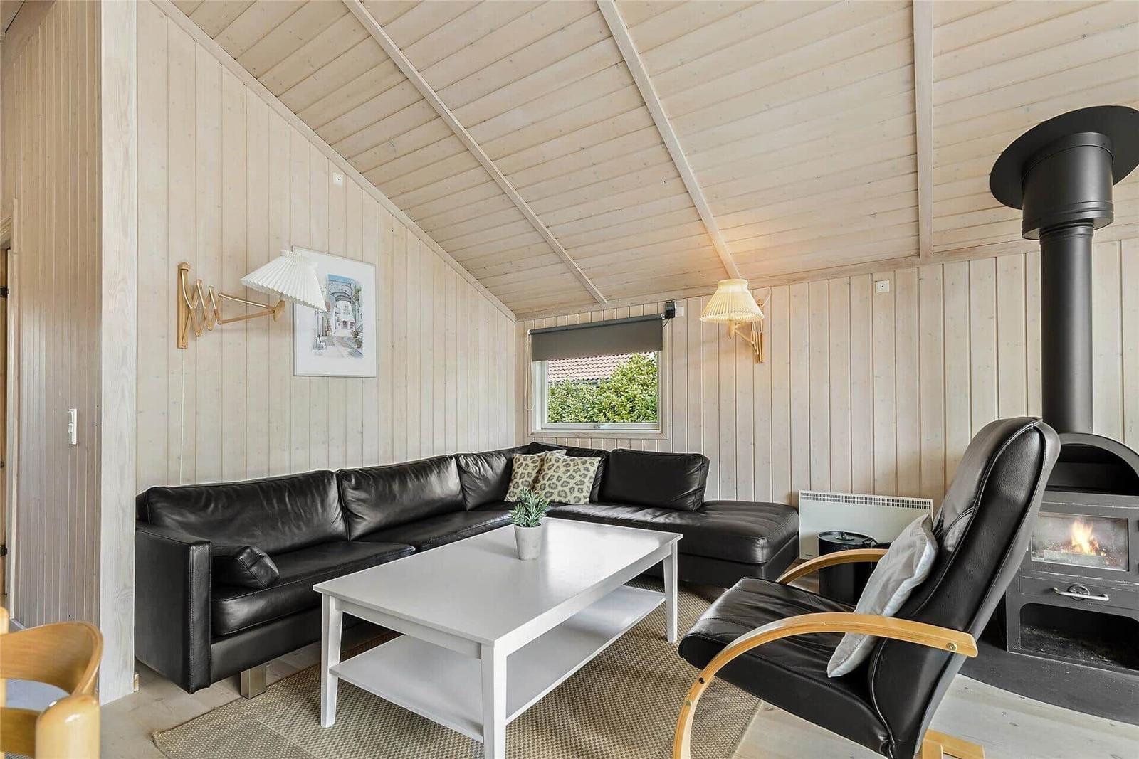 Ein Schlafzimmer mit Holzwand und -decke, Bett mit Kissen und Decke.
