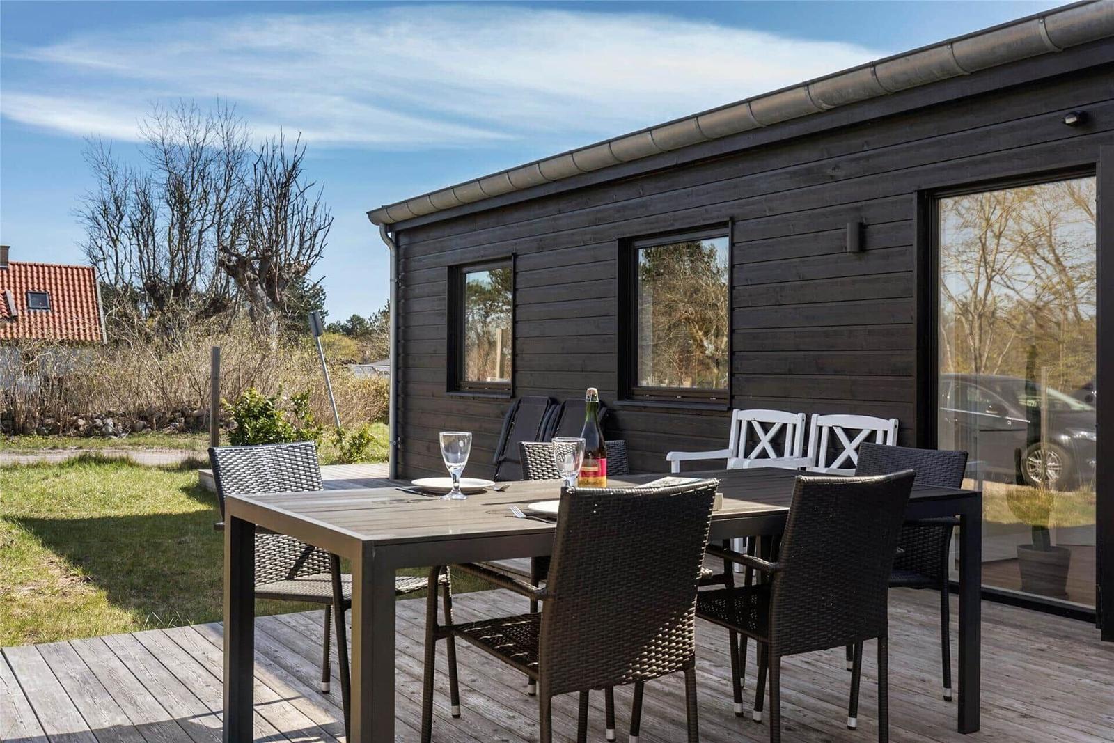Essbereich mit Holztisch, grauen Stühlen und großen Fenstern zur Terrasse.