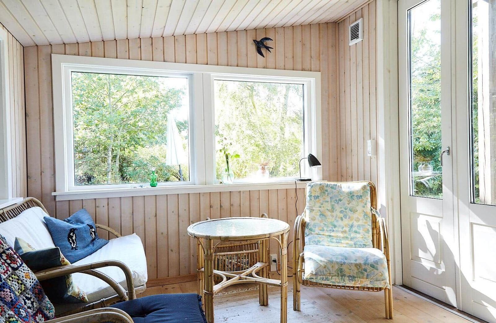 A bedroom with wooden walls, bed with blue cover, window and wall poster.