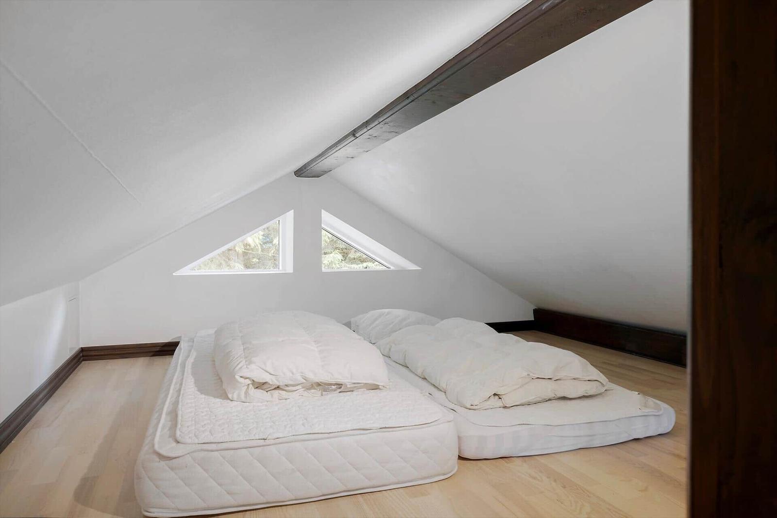 Mirror reflects bed and wall art in minimalist bedroom.