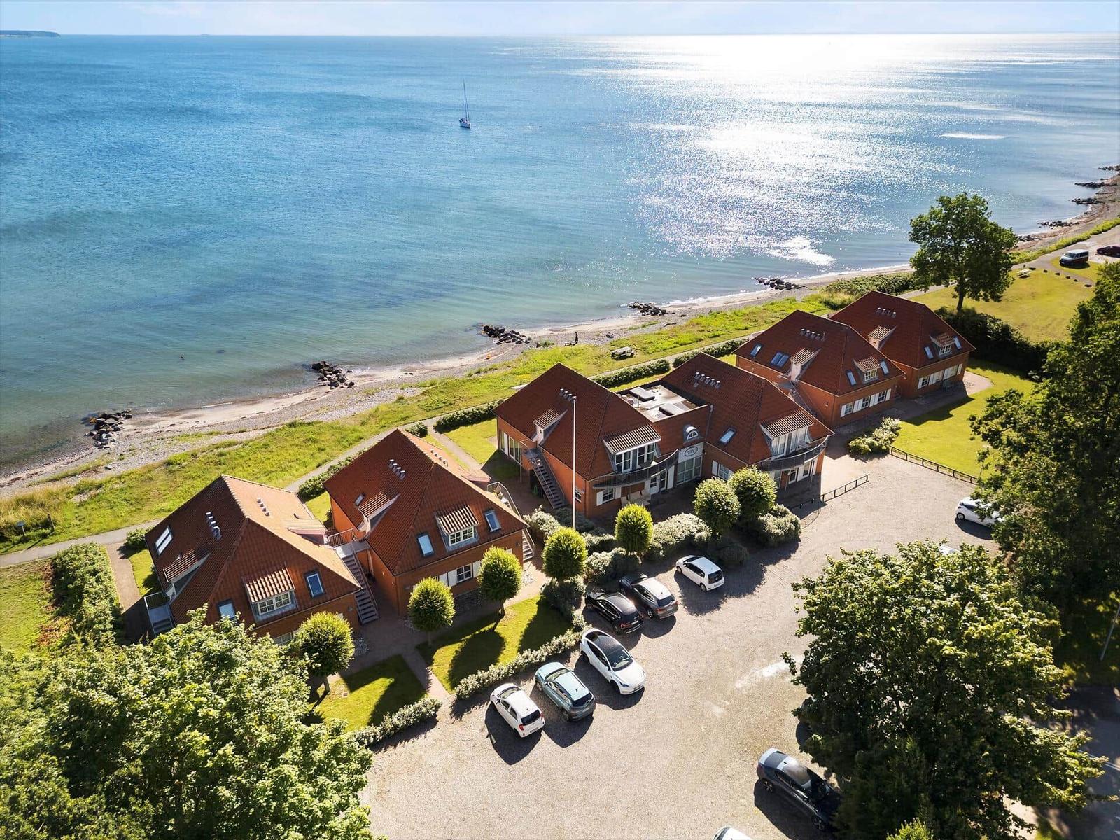Strandnahe Häuser mit Blick auf Wasser und Wald.