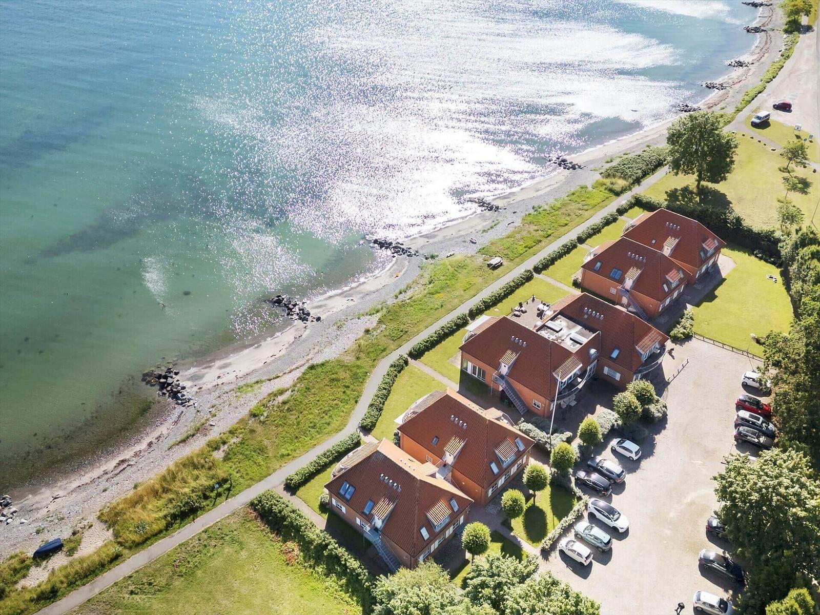 Luftbild von Ferienhäusern am Strand mit Grünflächen und Wasser.