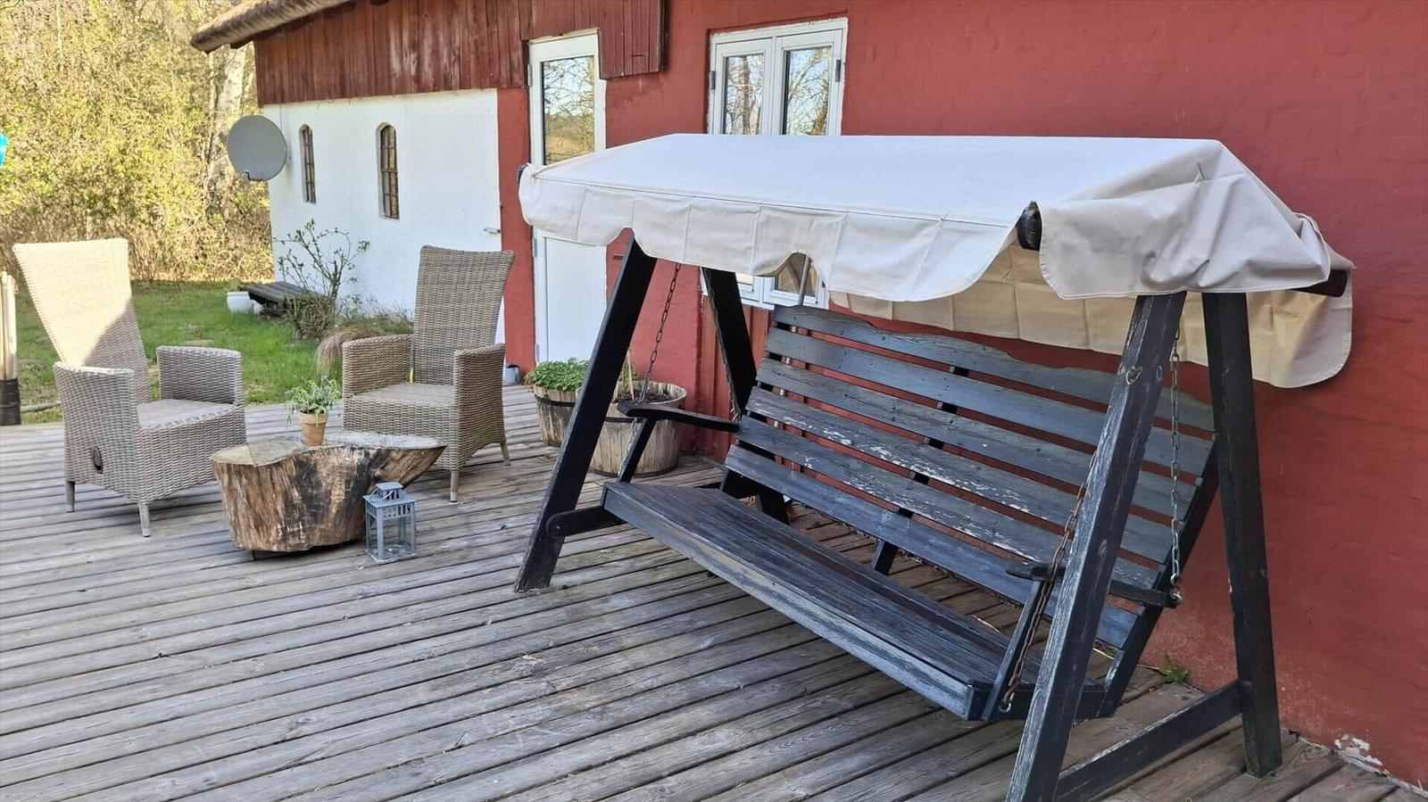 Haus mit strohgedecktem Dach und grünem Rasenfeld umgeben von Bäumen.