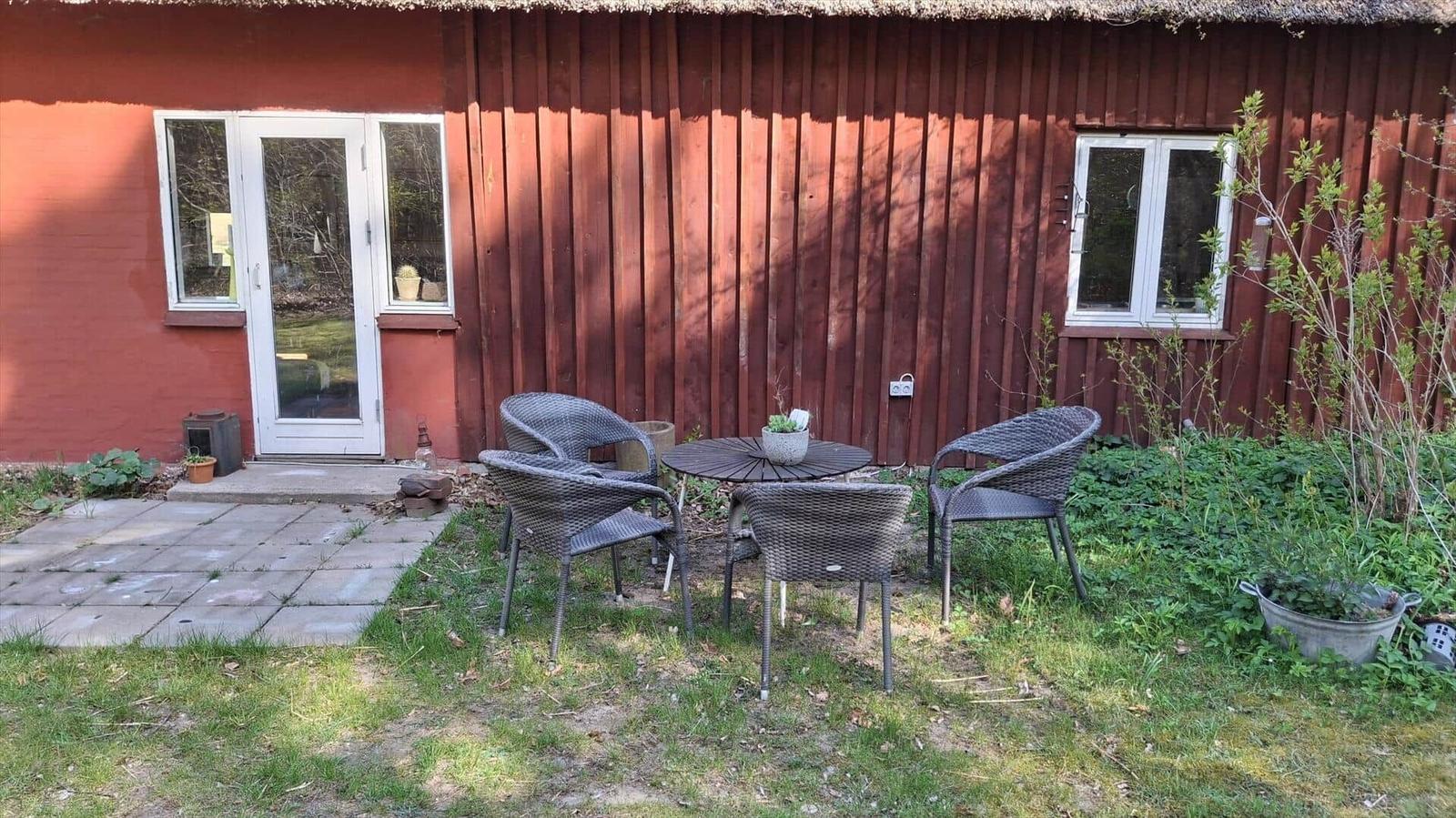 Ein Schlafzimmer mit einem Doppelbett und einem Holz-Kinderbett. Holzfußboden und Fenster mit Blick auf Grün.