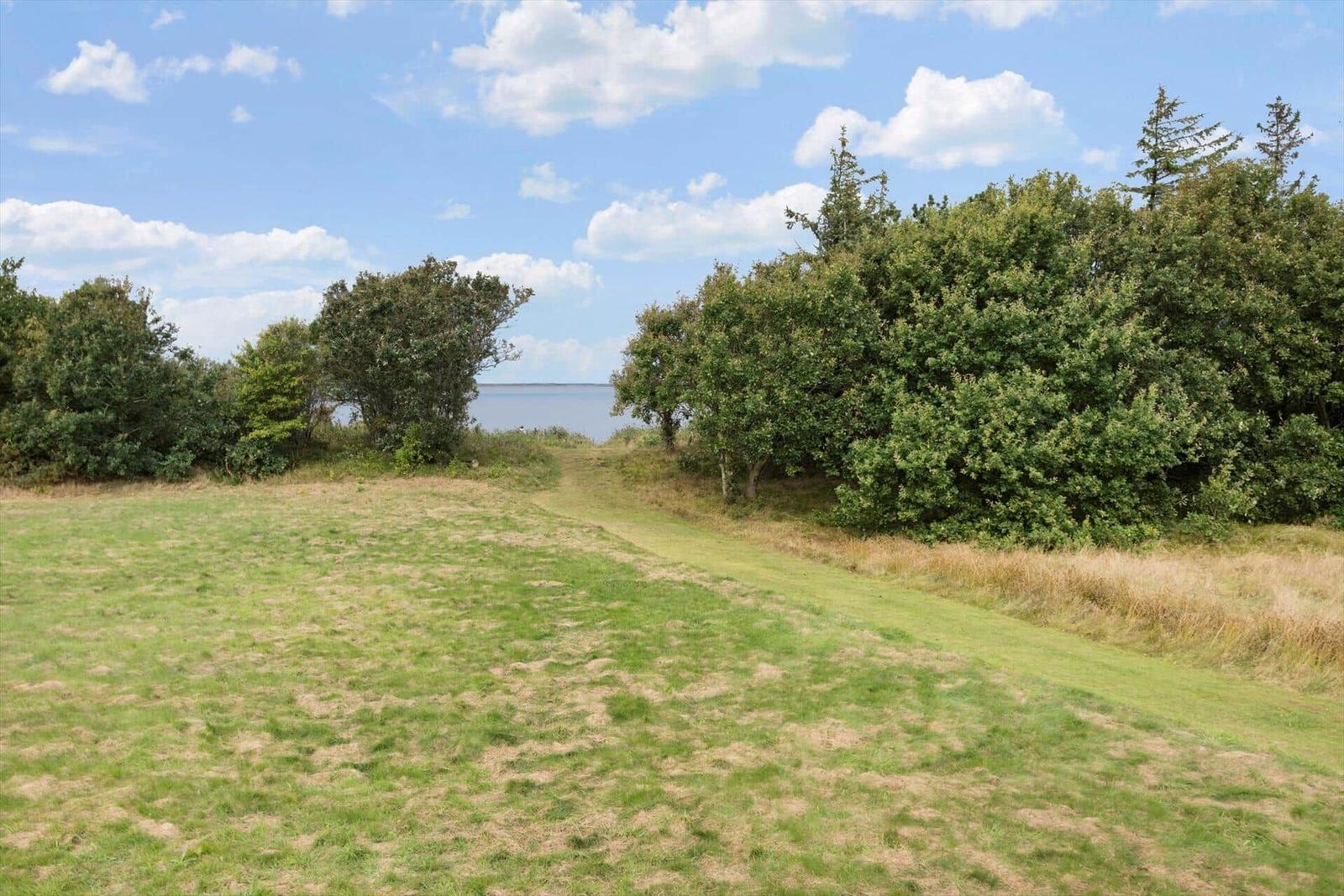Roter Flaggenmast vor Wasser mit Bootshäusern im Hintergrund.