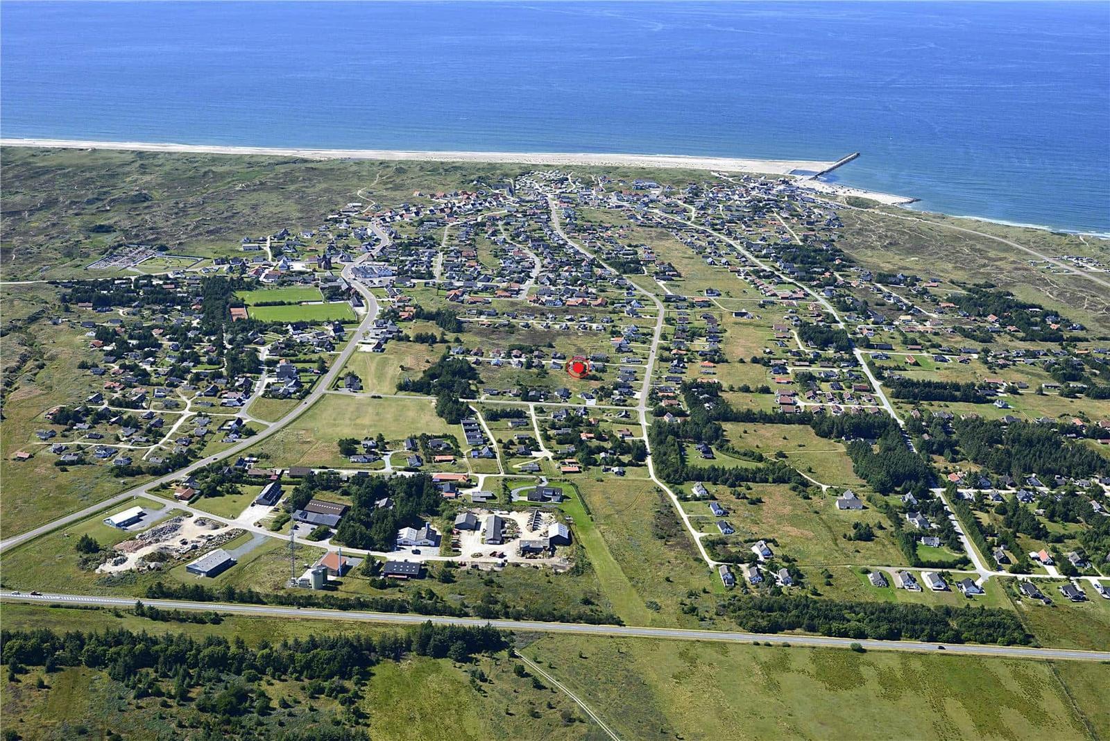 Luftbild einer Küstenstadt mit Strand, Häusern und Grünflächen.