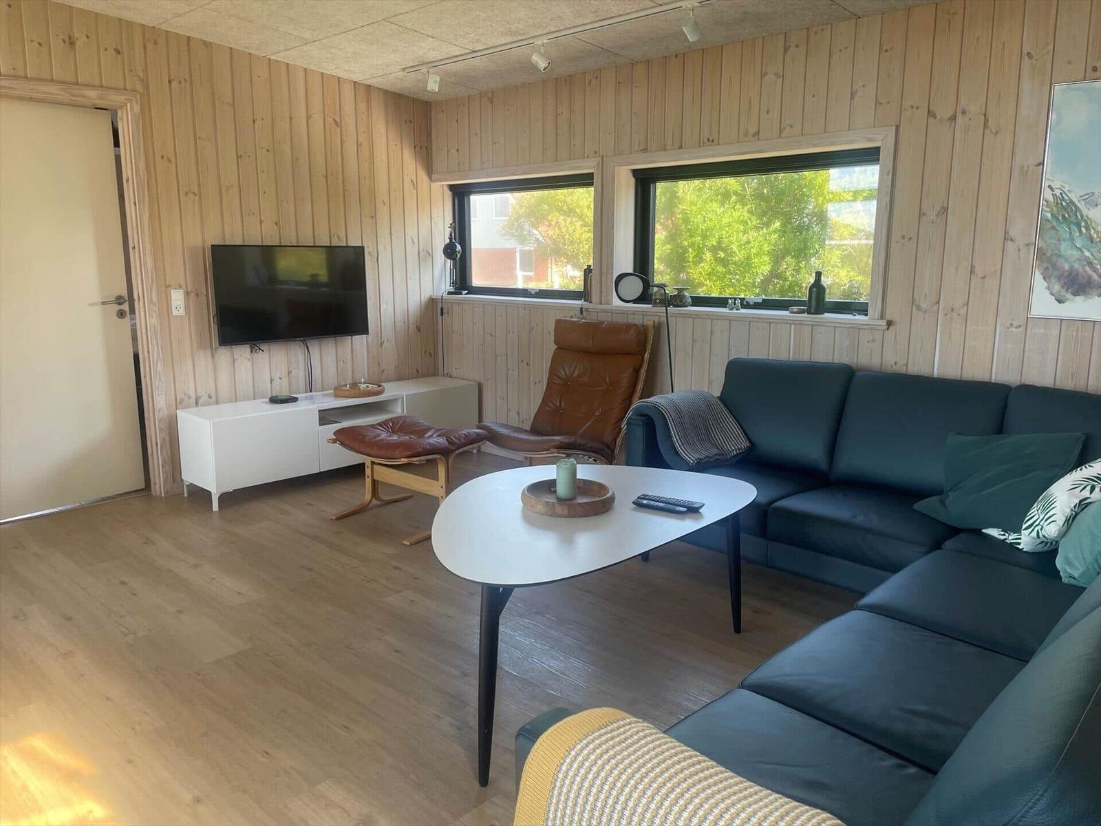 Living room with sofa, TV, and windows for outdoor views.
