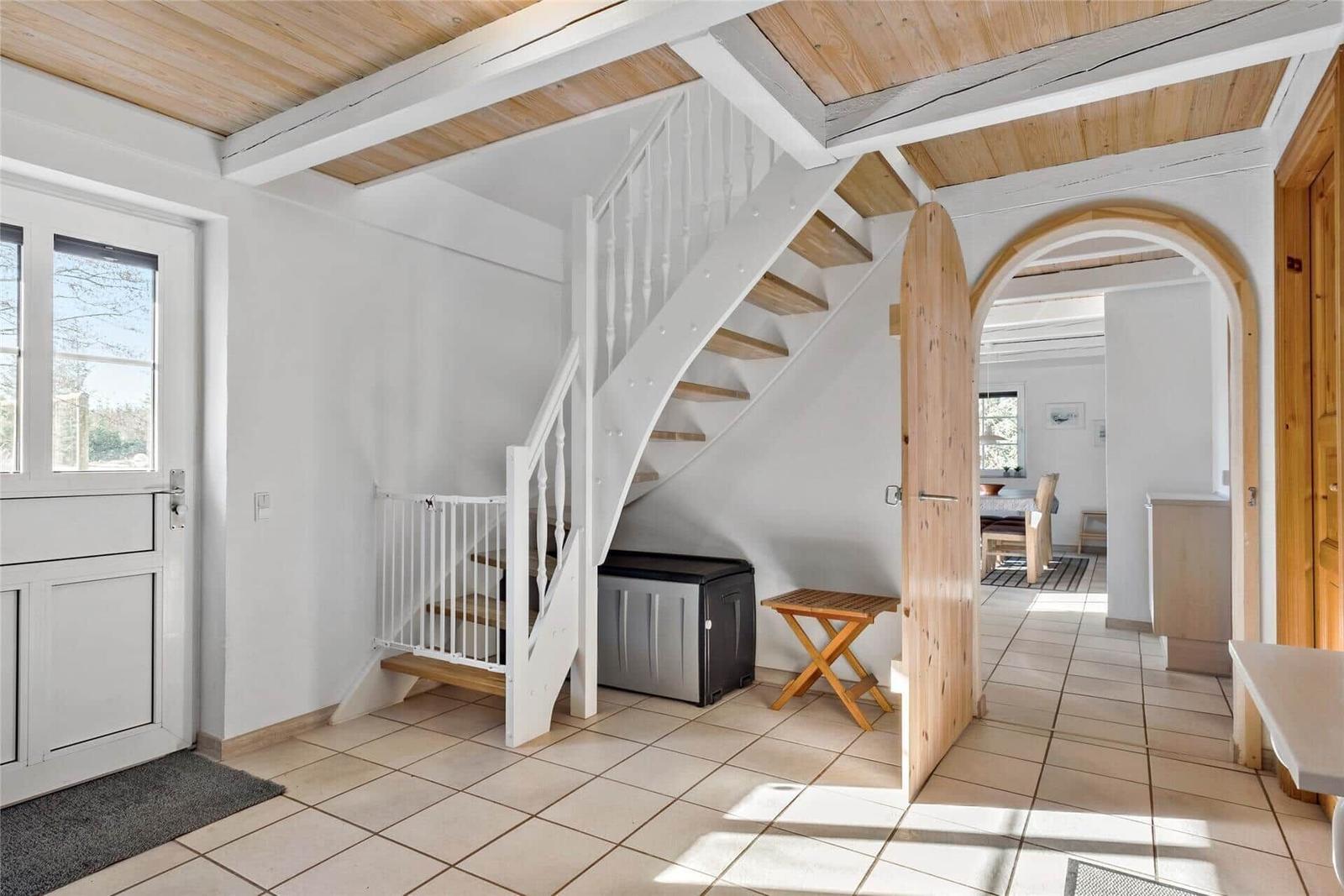 Eingangsbereich mit Treppe, Tür und Blick in die Küche.