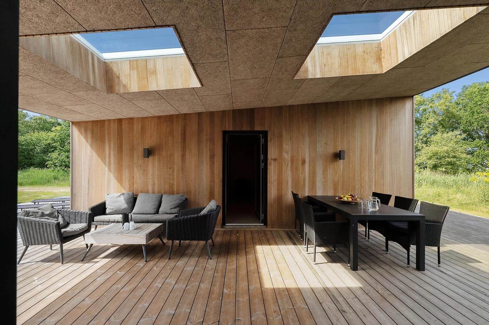 Dining area with wooden table and chairs. Large windows with view of the landscape.