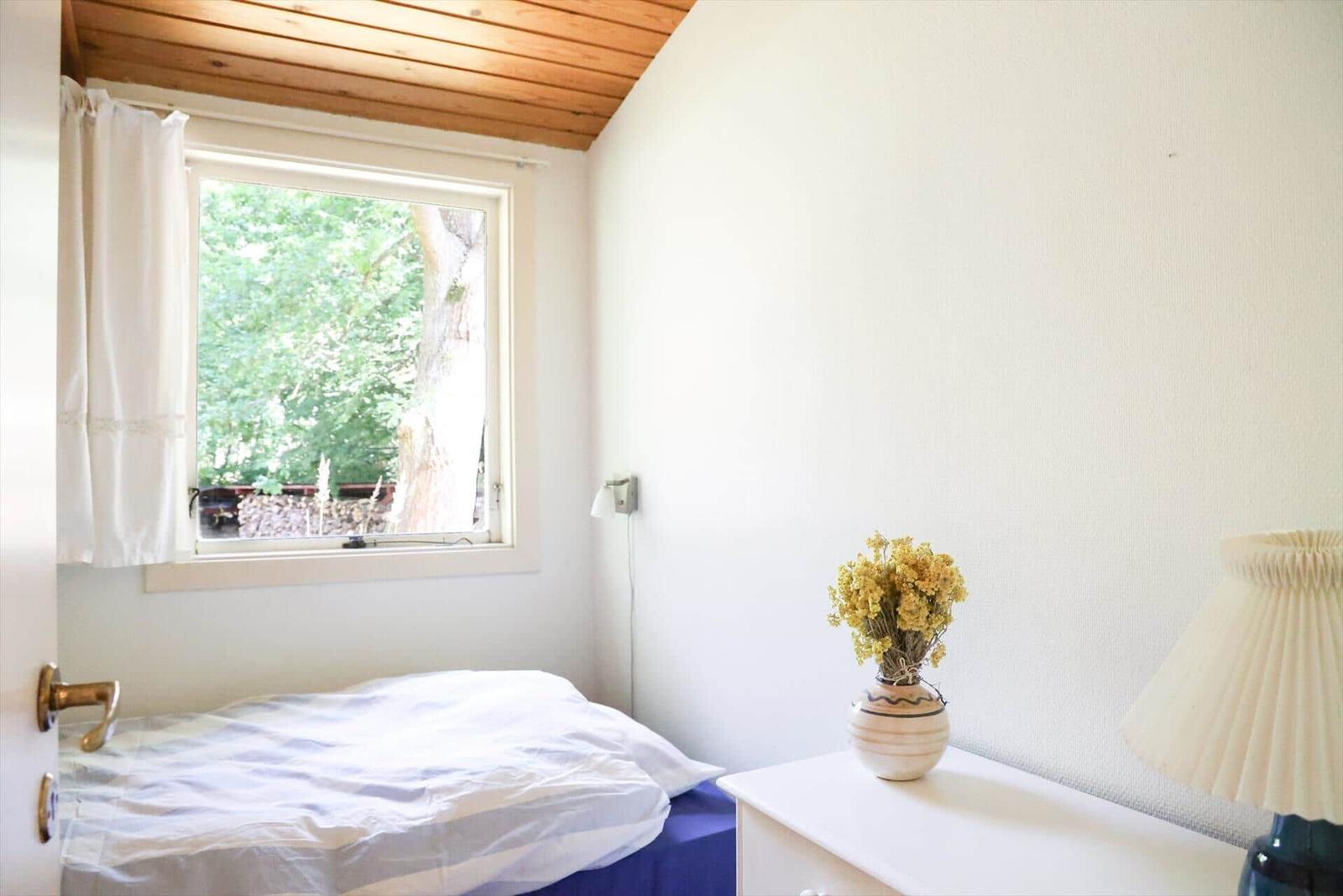 Rotes Ferienhaus mit Garten und Bäumen. Außentisch und Sitzgelegenheit.