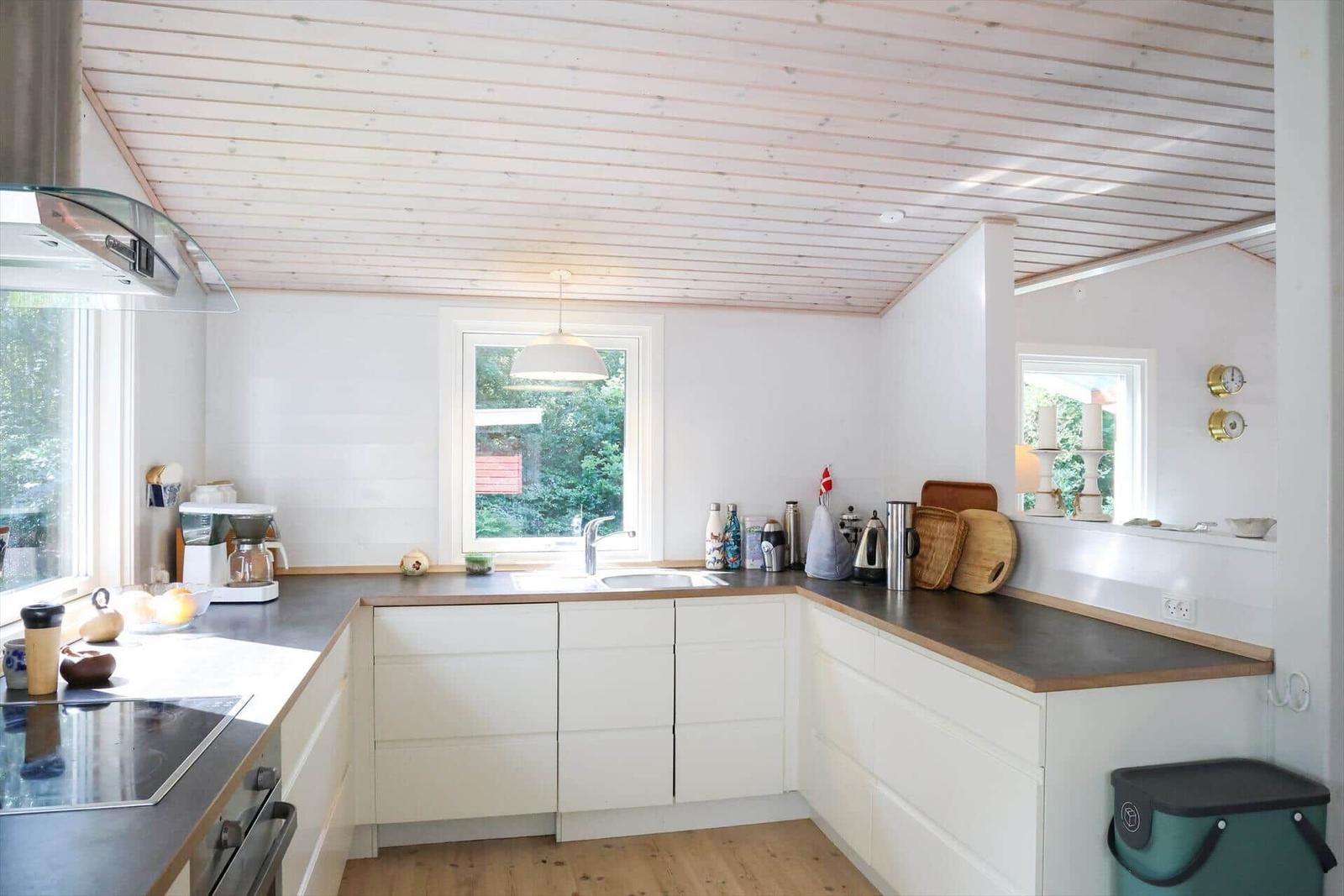 Flur mit Holzboden, Schrank und Lampen. Durchgang zu Schlafzimmer mit Bett und Kleiderständer.