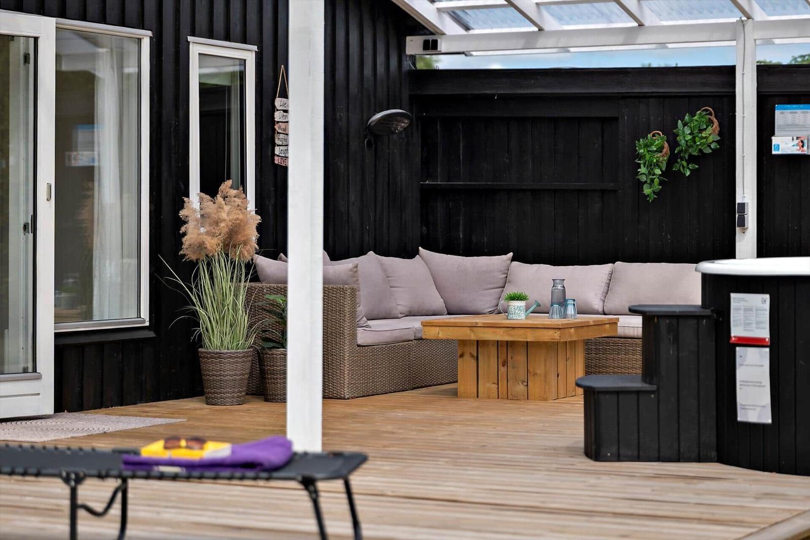Wooden terrace with hot tub, sun cover, and garden furniture.