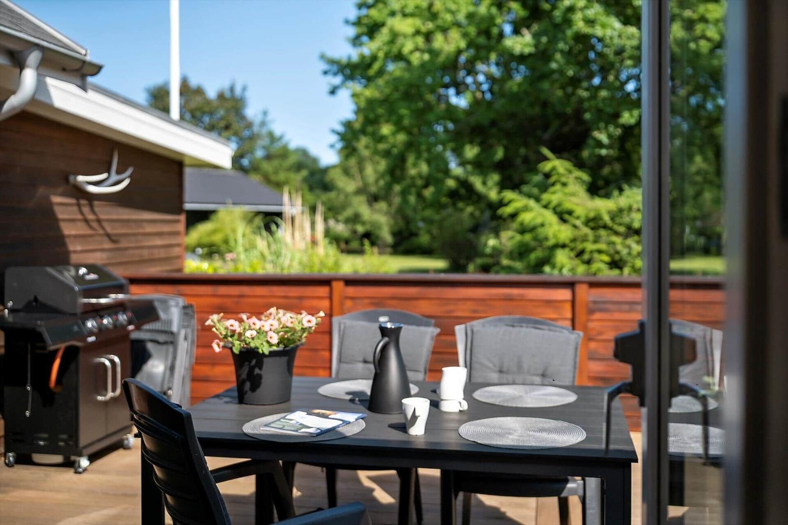 Holzhaus mit Terrasse, Grill und Garten. Gepflegte Außenanlage mit Blick auf Wald.