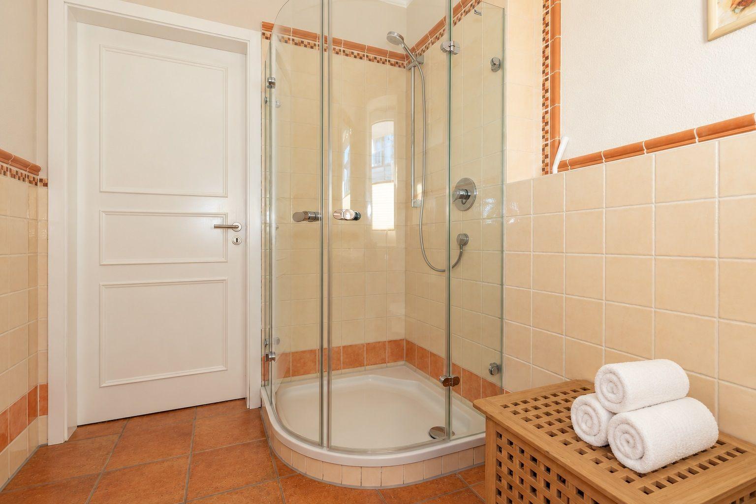 Badezimmer mit Dusche, Toilette, Waschbecken und Fenster.