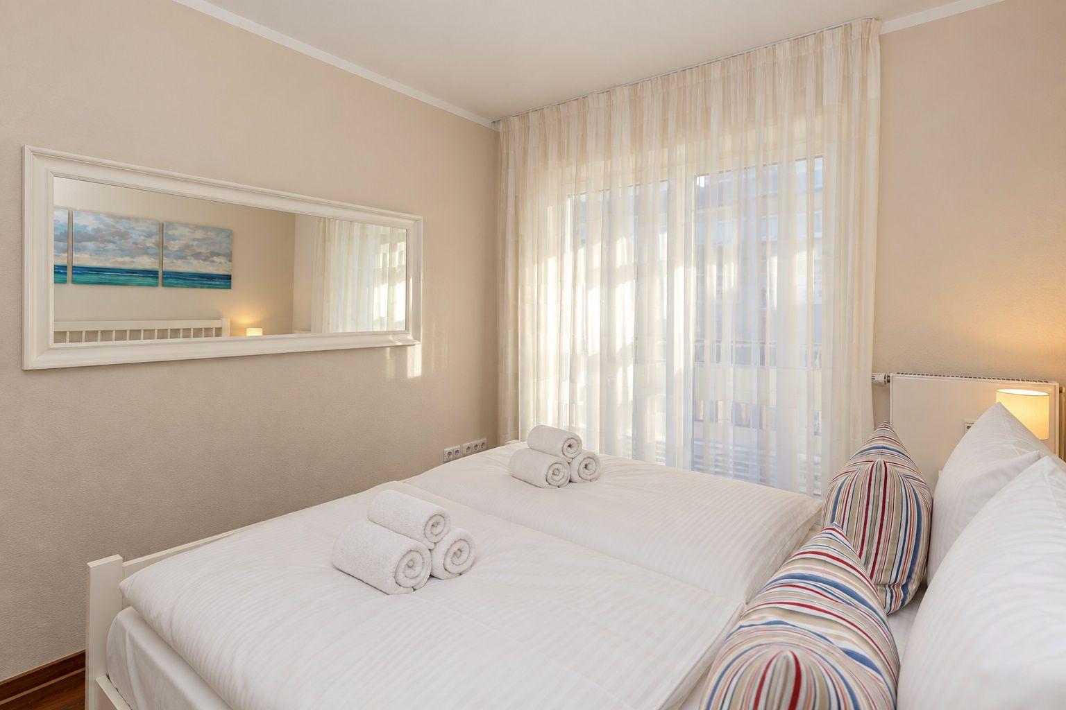 Zimmer mit Bett, Schlafcouch, Nachttisch und Wandbild.