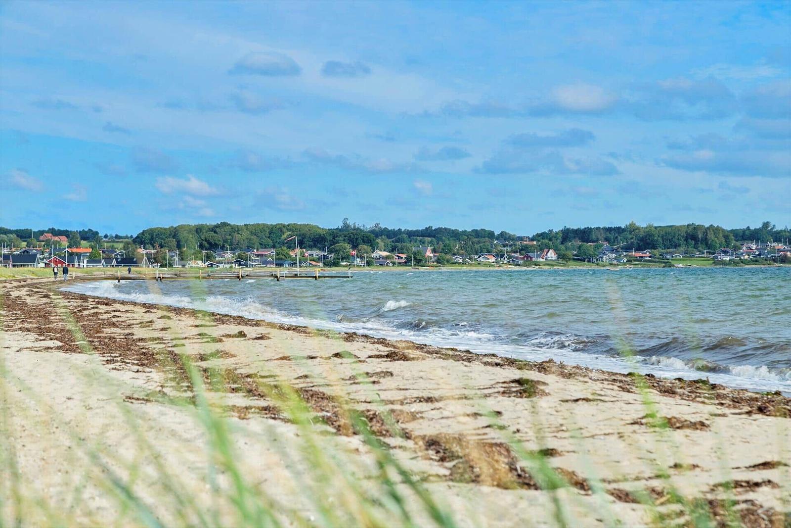 Großer Spielplatz mit Sandkasten, Klettergerüst und Schaukelanlage vor einem Haus mit Blick aufs Wasser.