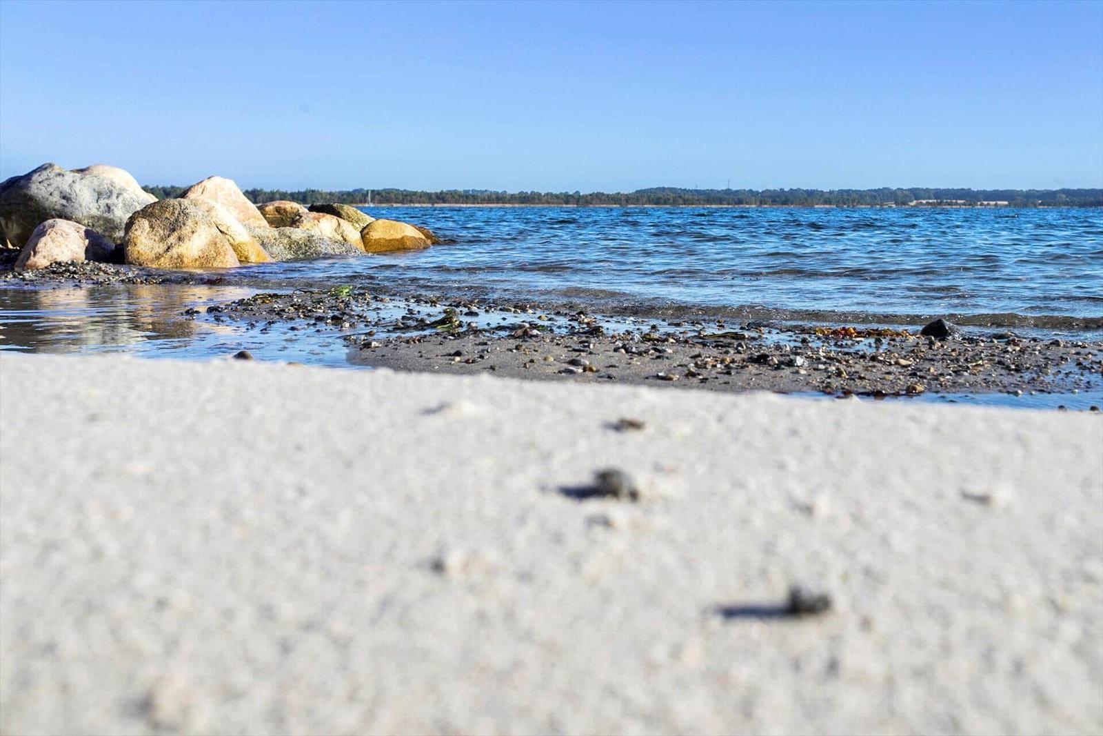 Aeriale Aufnahme eines Hafens mit Booten, Strand und Wohnbereichen an der Küste.