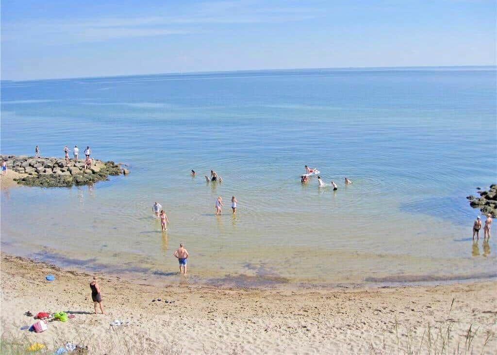 Beach with clear water and people swimming or standing.