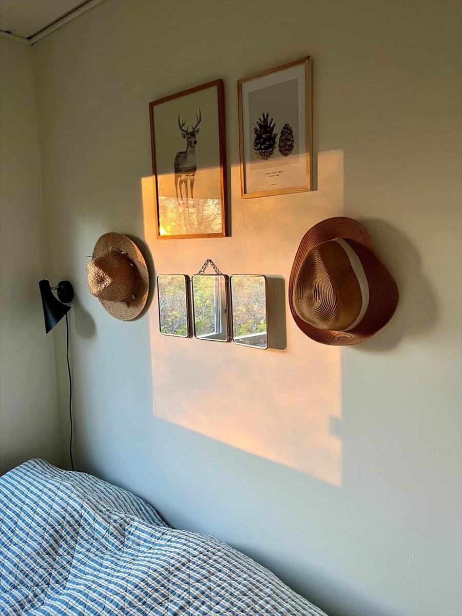 Ein Wohnzimmer mit Sofa, Kissen, Tisch und Fenstern. An der Wand hängen Bilder.