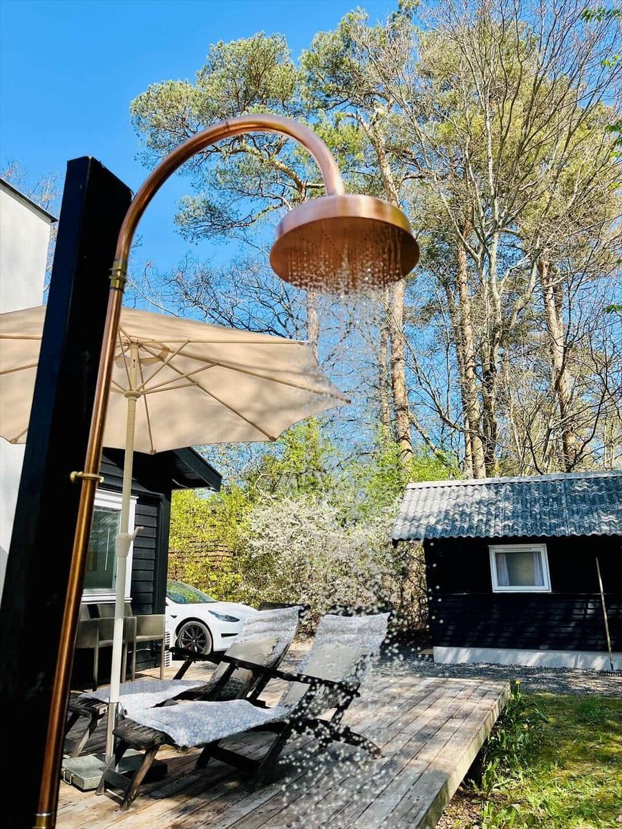 Wohnzimmer mit Holzmöbeln, Wandbildern und Fenstern. Holzdielenboden und Sitzgelegenheiten.