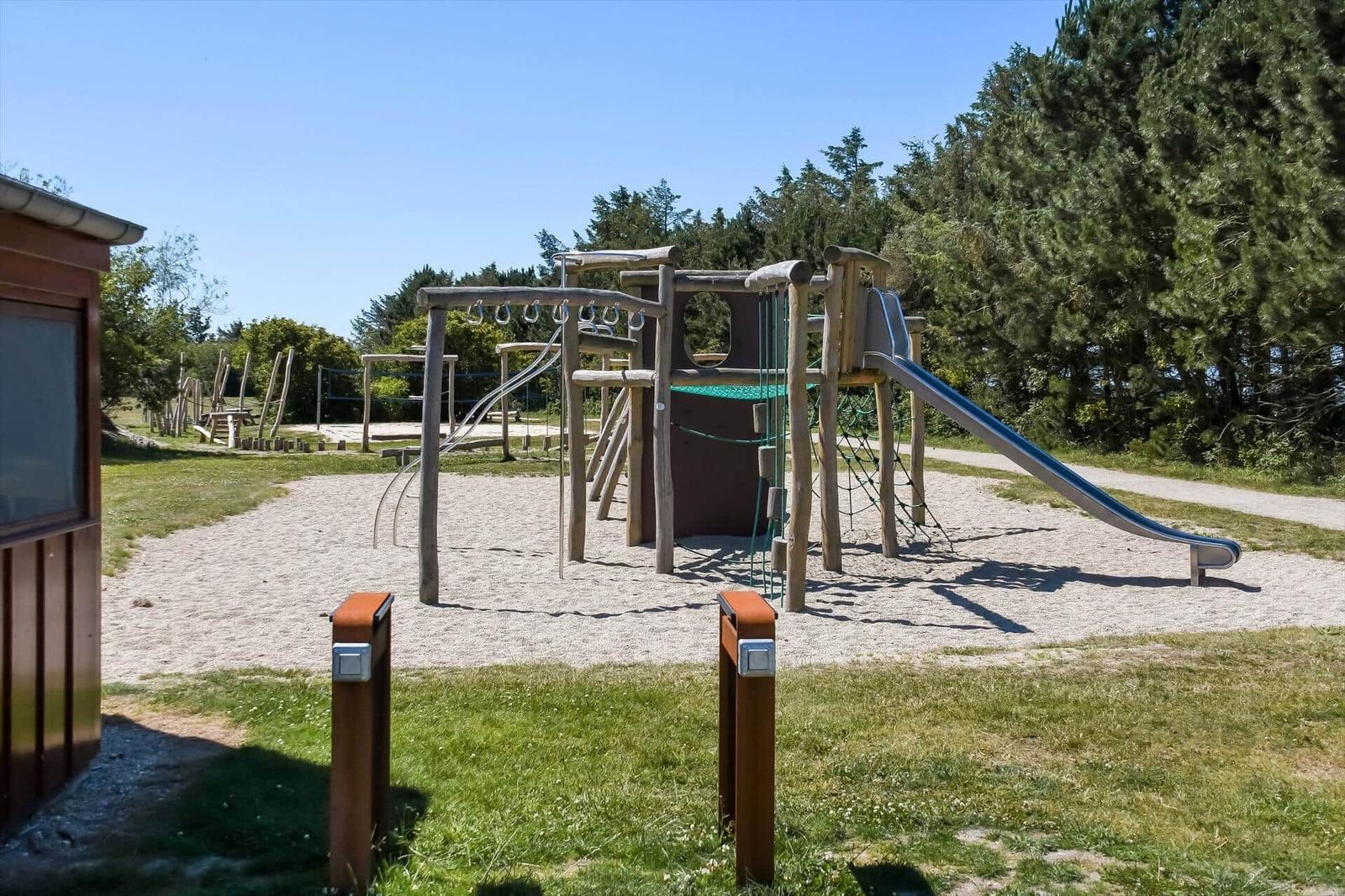 Holzspielplatz mit Rutsche und Klettergerüst auf Sandfläche