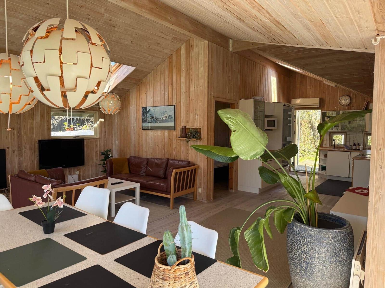 Living and dining area with wood walls, sofa, table, and chairs.