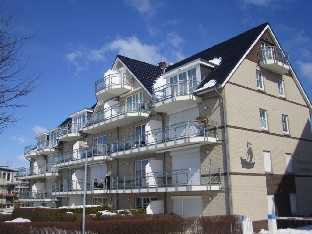 Strand mit Liegestühlen, Holzweg und Strandhütte unter blauem Himmel.