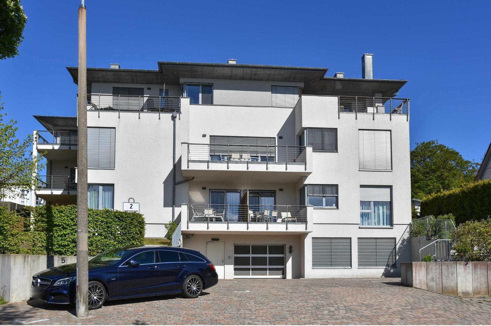 Modern apartment with balconies and garage. A car is parked on the driveway.