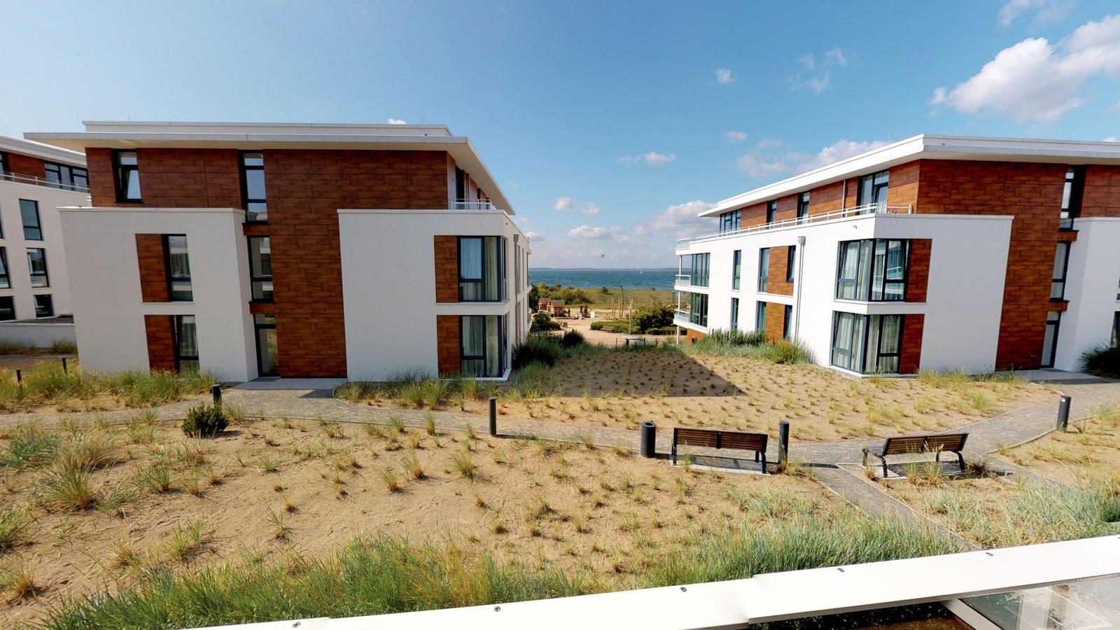 Holiday apartment in modern building complex with view of coastal landscape and forest.