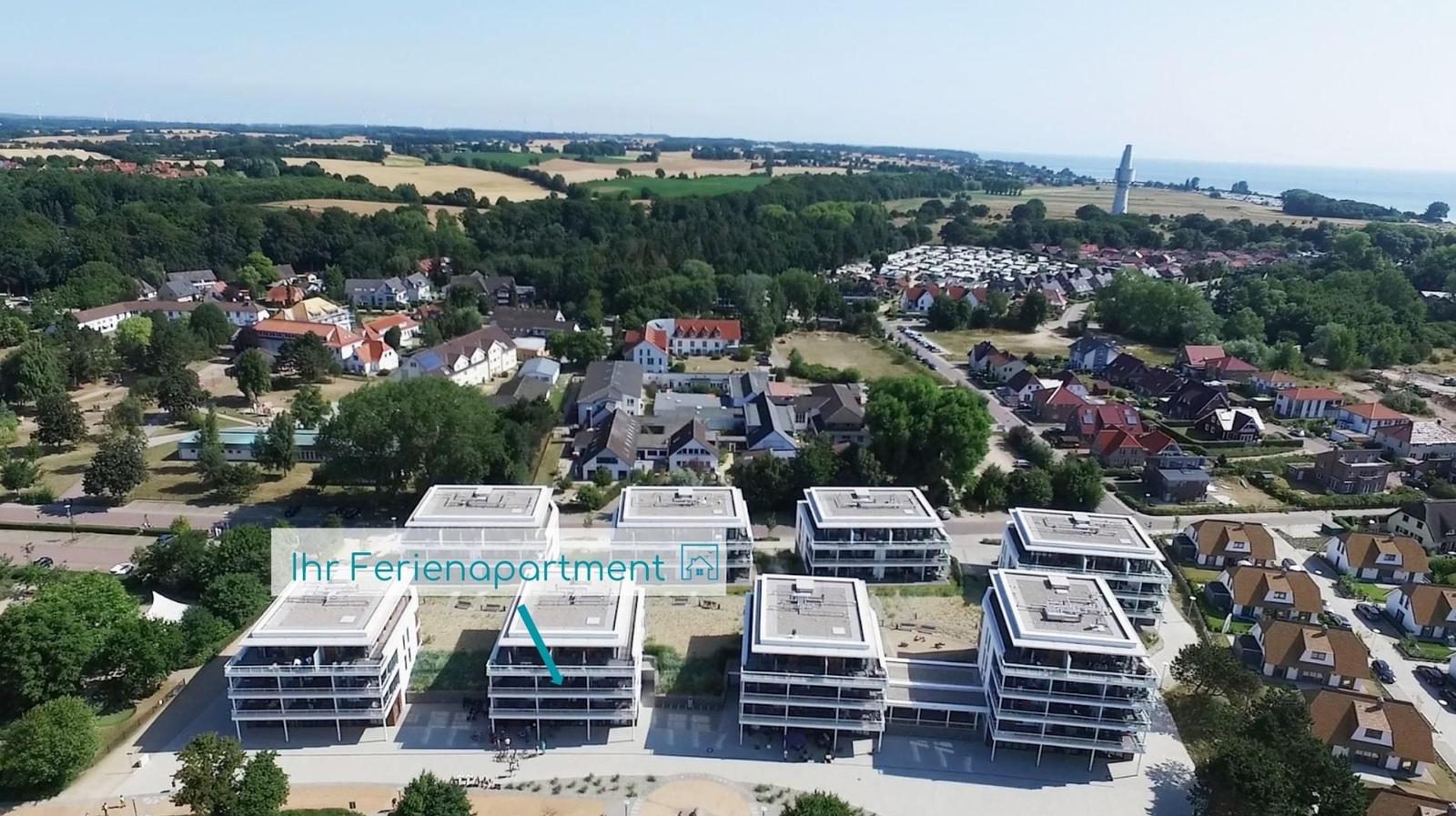 Holiday apartment in modern building complex with view of coastal landscape and forests.